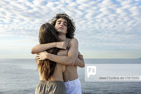 Junge  oben ohne Freundin und Freund umarmen sich vor dem Meer