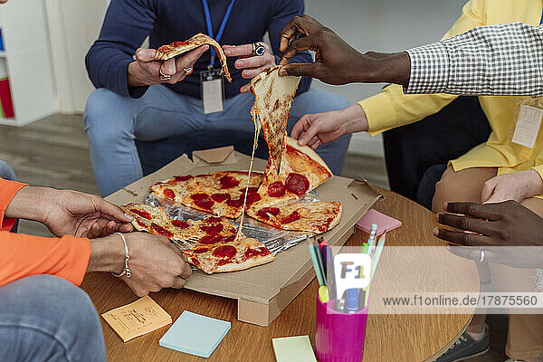 Hands of business colleagues holding pizza slices in office