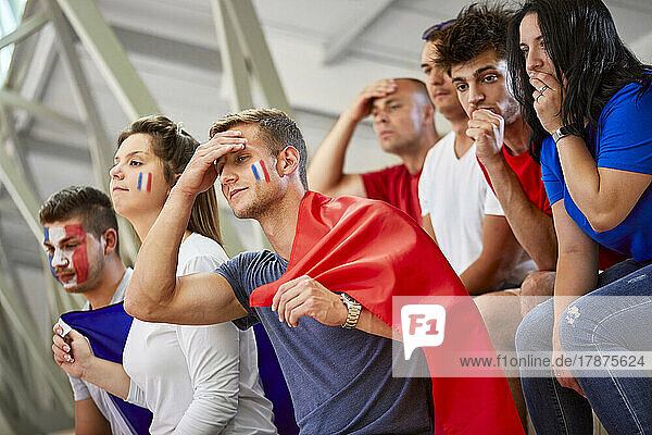 Worried fans watching sports event at stadium