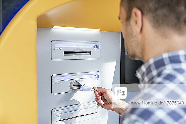 Mann führt Kreditkarte in Geldautomaten ein