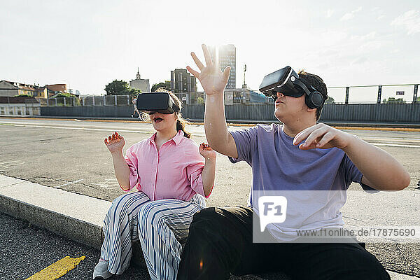 Teenage girl and boy wearing VR goggles on city street