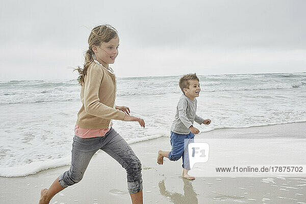 Bruder und Schwester haben Spaß beim Laufen am Strand