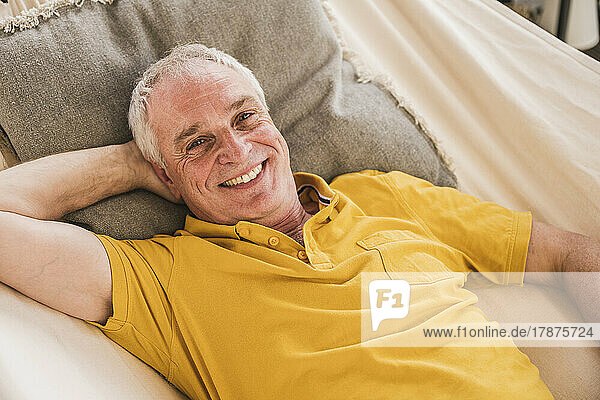 Happy man with hand behind head relaxing in hammock