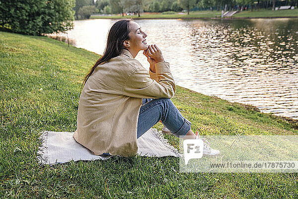 Frau sitzt am See im Park