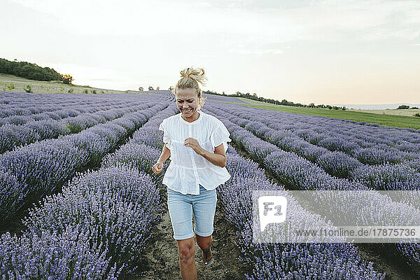 Happy woman running amidst lavender plants