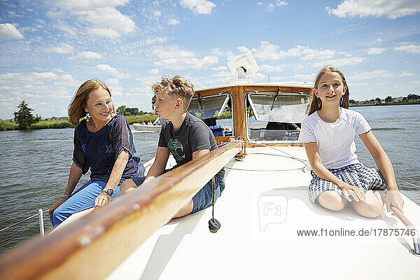Siblings with grandmother sitting on boat deck at vacation