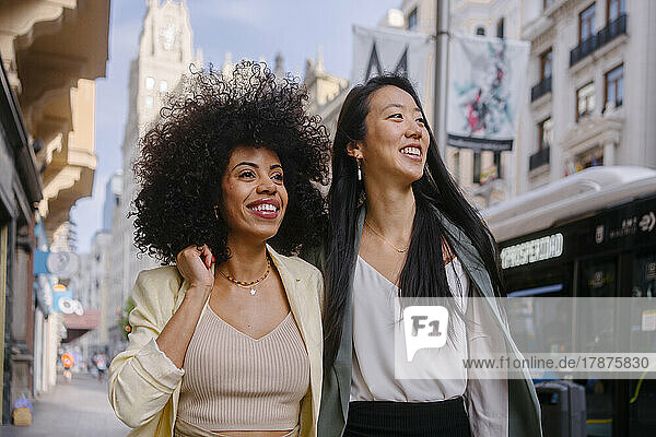 Smiling woman with friend strolling in city