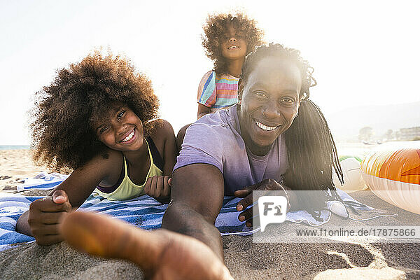 Glücklicher Vater mit Töchtern  die auf einem Strandtuch liegen