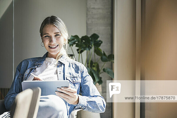 Happy businesswoman with tablet PC in office