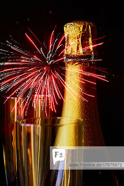 Bottle of champagne against exploding fireworks