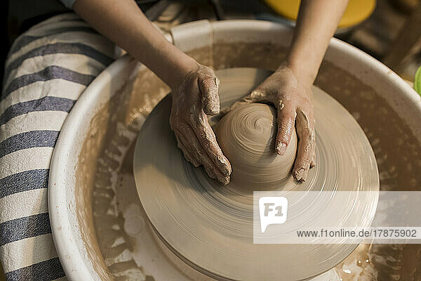 Hands of potter moulding shape on pottery wheel