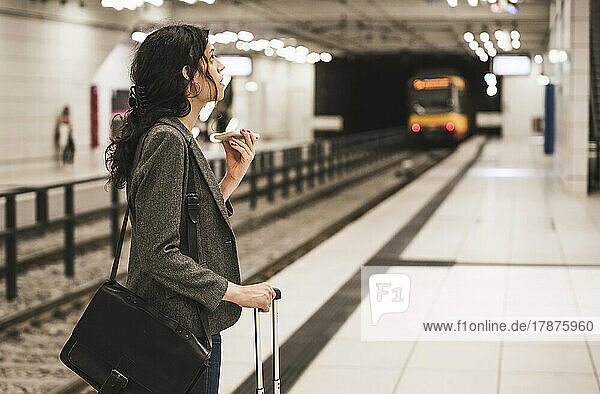Transgender businesswoman wearing blazer talking on phone standing at subway station