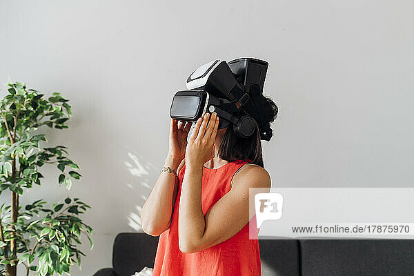 Woman wearing virtual reality simulator at home