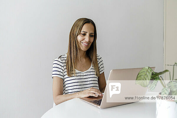 Smiling freelancer working on laptop sitting at home office