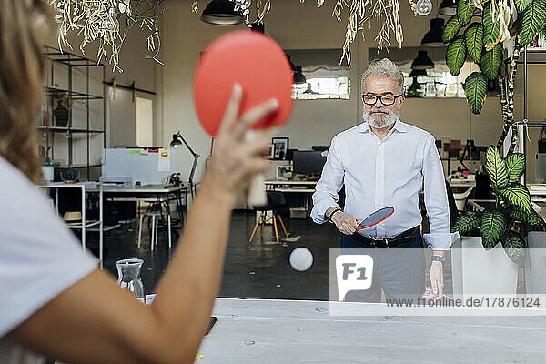 Manager playing table tennis with colleague at office