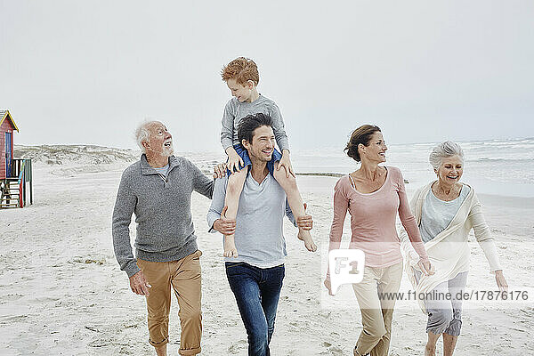 Happy couple spending quality time at the beach with son and grandparents