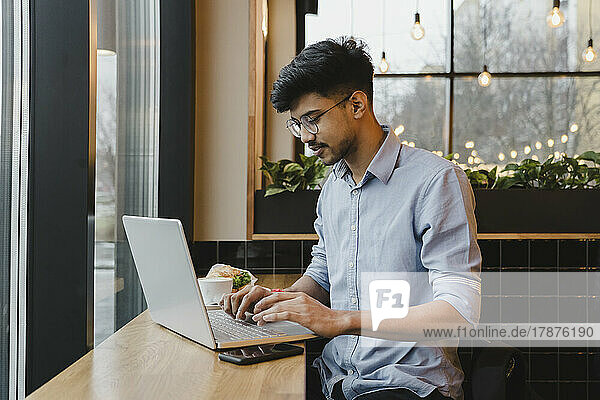 Young freelancer working on laptop at cafe