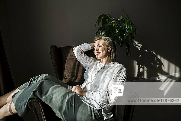 Smiling mature woman relaxing in chair at home