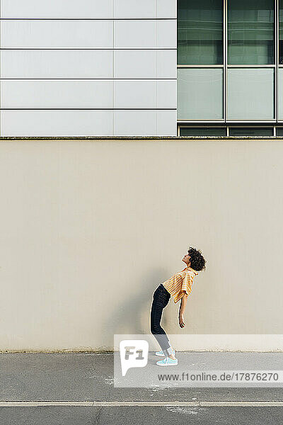 Woman bending backwards in front of wall