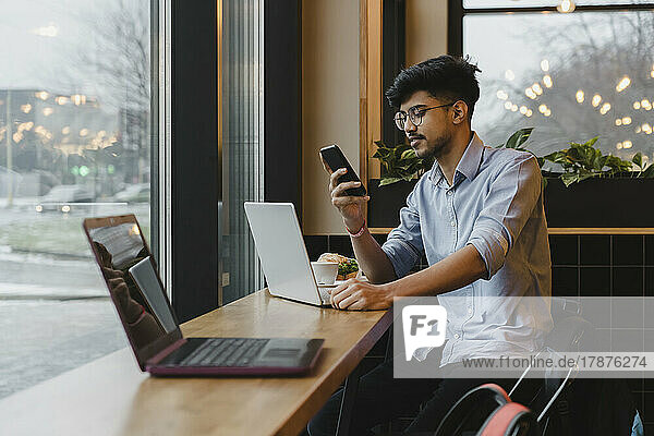 Young freelancer using smart phone in cafe