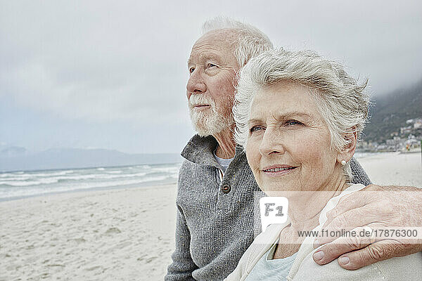 Senior couple standing on the beach with arms around