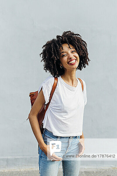Smiling woman with curly hair in front of wall