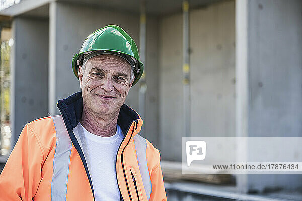 Lächelnder Bauunternehmer steht auf der Baustelle