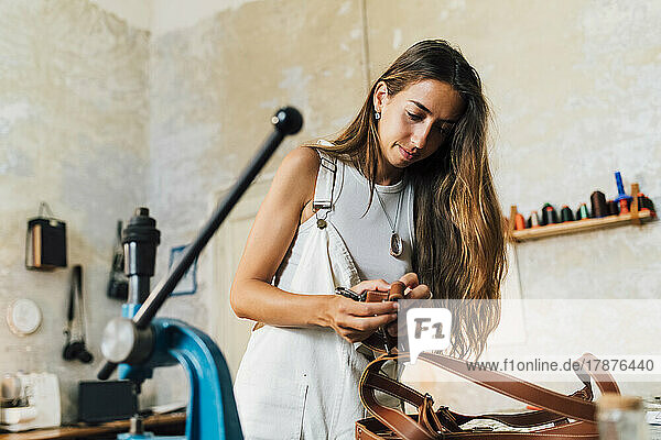 Fashion designer making leather accessory at workshop