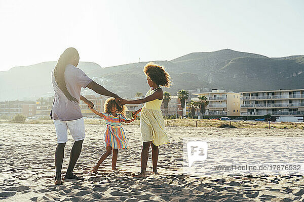 Father with daughters playing ring around rosy at beach