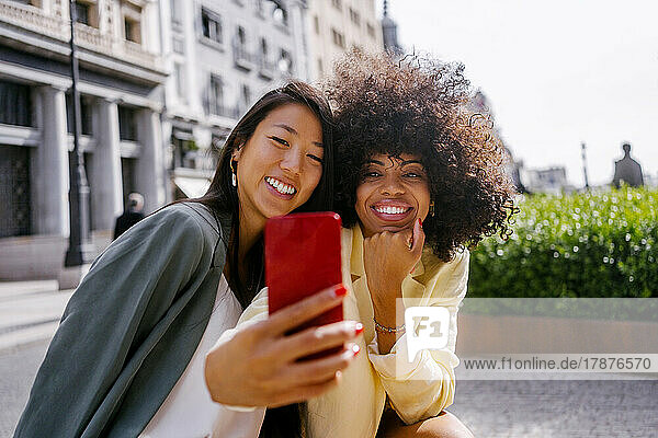 Woman taking selfie with friend through smart phone