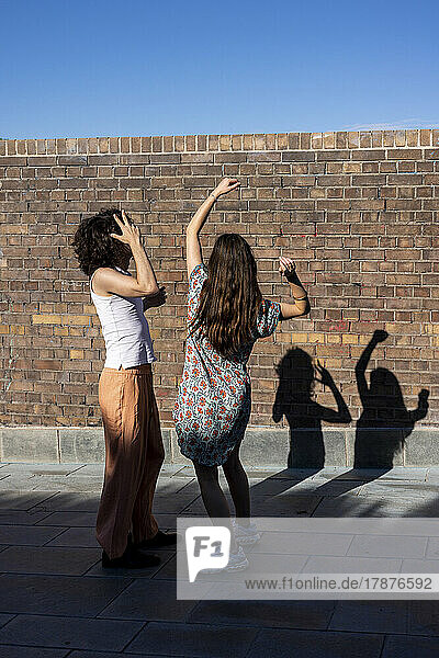 Junges Paar tanzt an einem sonnigen Tag vor der Wand