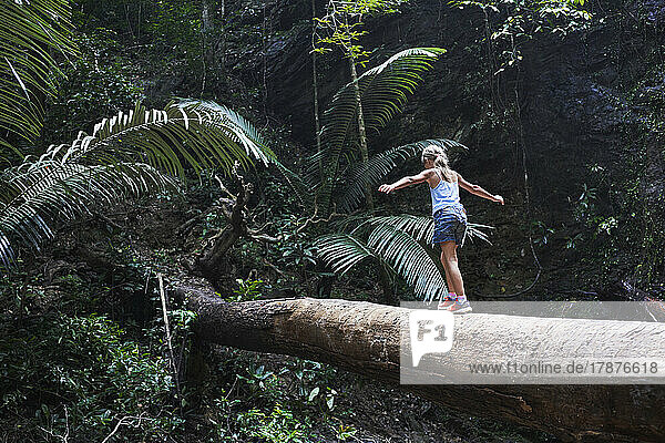 Girl balancing on fallen tree trunk in forest