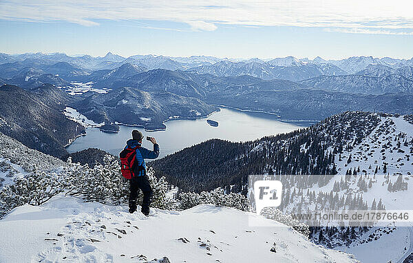Hiker photographing Walchensee and Bavarian Prealps from Mt. Herzogstand  Bavaria  Germany