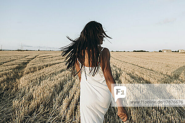 Woman with tousled hair walking at wheat field