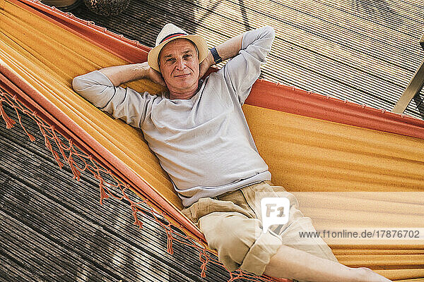 Senior man wearing hat relaxing in hammock
