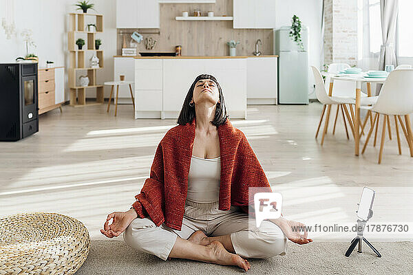 Woman sitting cross-legged doing meditation at home