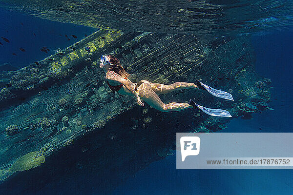 Woman swimming by shipwreck in sea