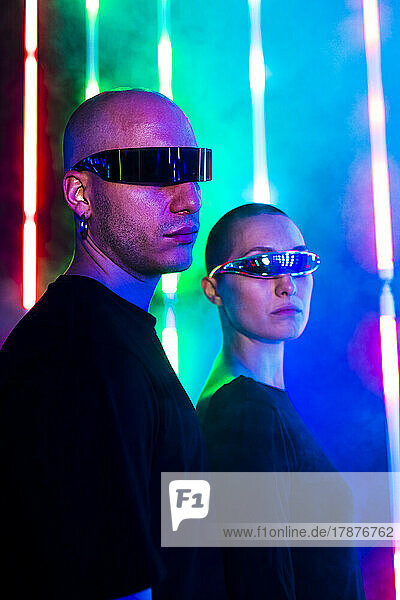 Man wearing smart glasses with woman by illuminated lights