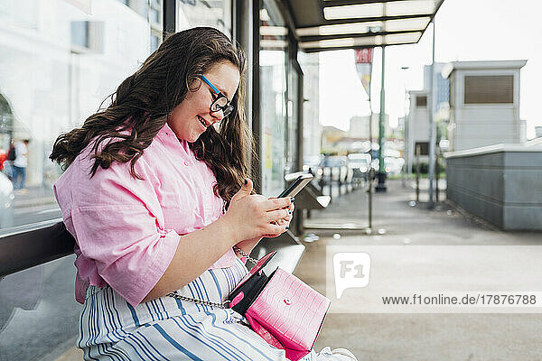 Teenage girl with down syndrome using mobile phone at bus station