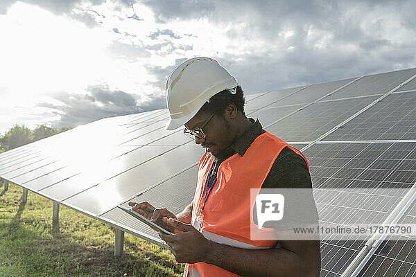 Man with hardhat using tablet PC at solar station