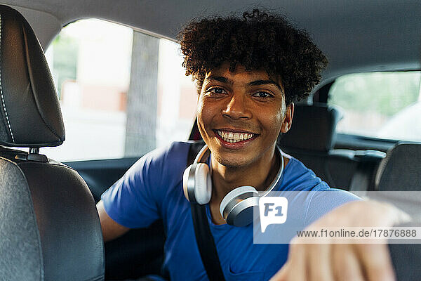 Happy man with wireless headphones sitting in car