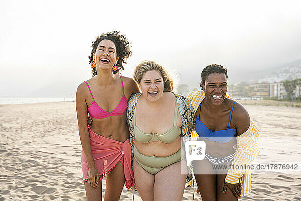 Multiracial friends laughing at beach on vacation