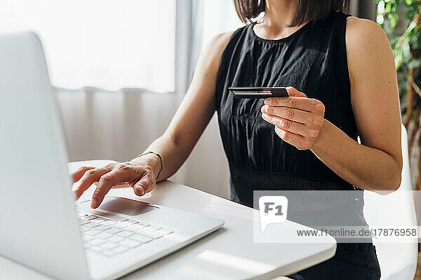 Woman holding credit card doing online shopping through laptop