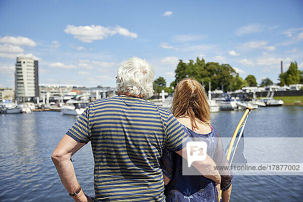 Senior man with arm around woman looking at harbor