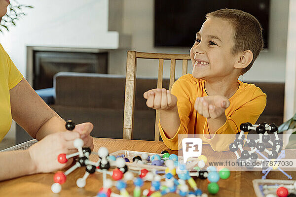 Lächelnder Junge schaut seine Mutter mit dem Helix-Modell auf dem Tisch an