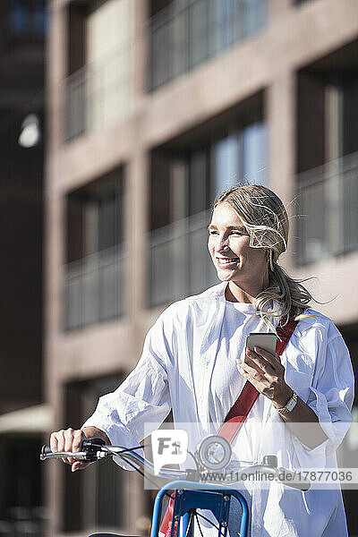 Happy woman with bicycle and smart phone on sunny day