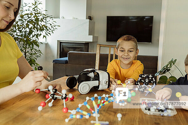 Lächelnder Junge  der das DNA-Modell auf dem Tisch betrachtet