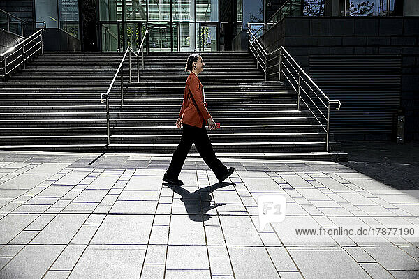 Businesswoman walking on footpath near office building