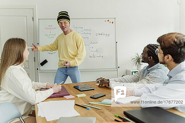 Happy businessman giving presentation to colleague at office