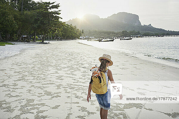 Mädchen mit Rucksack spaziert am Strand